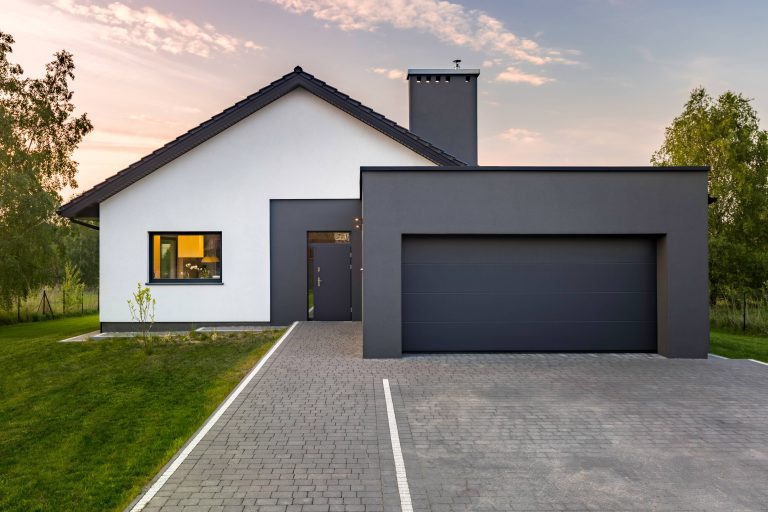 New home Construction in Palo Alto, California. we see the exterior of a modern home. very minimalist and clean White House with a black garage and a black entrance door.